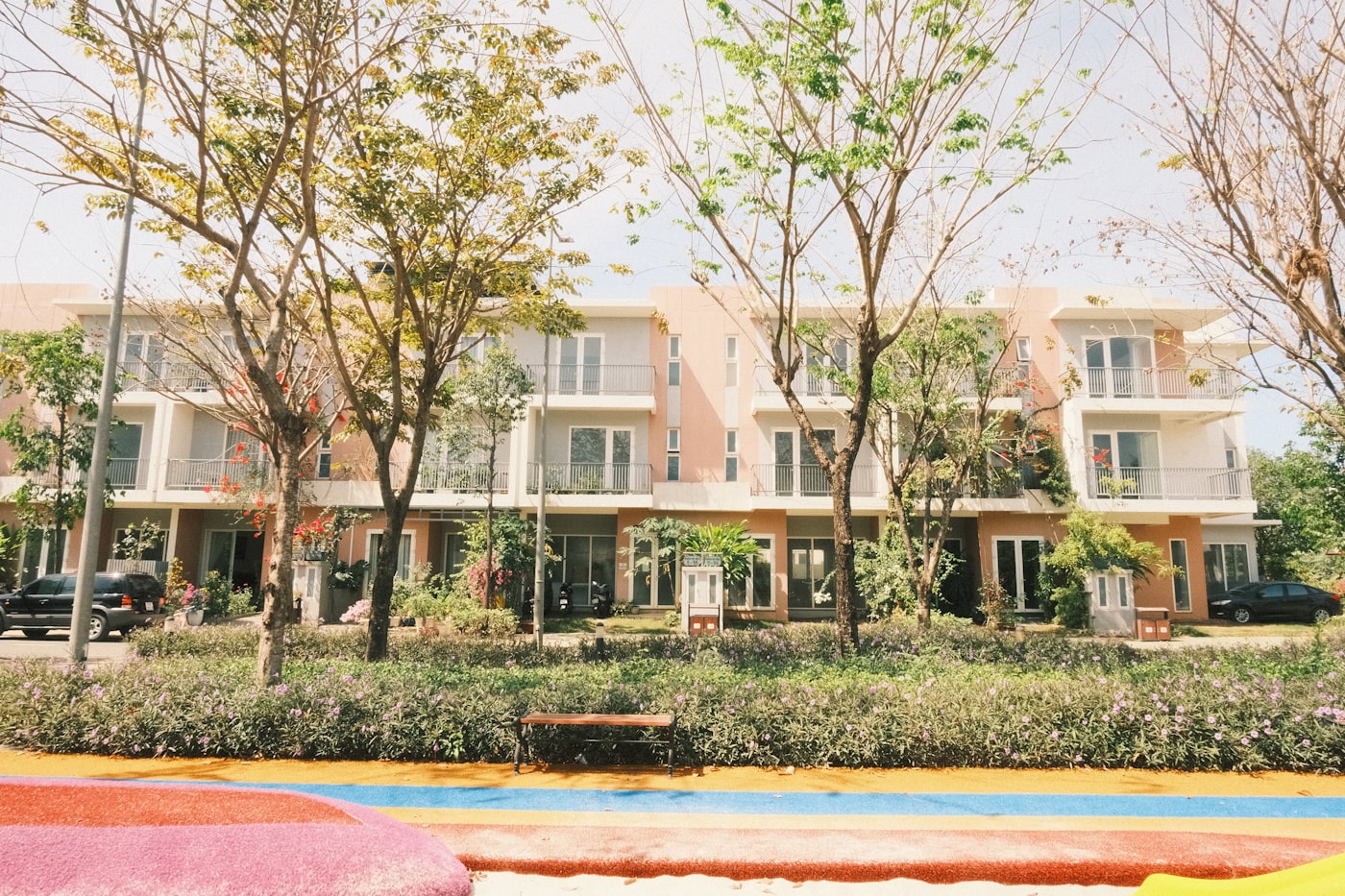 Tree-lined row of modern terrace homes behind flowering hedges